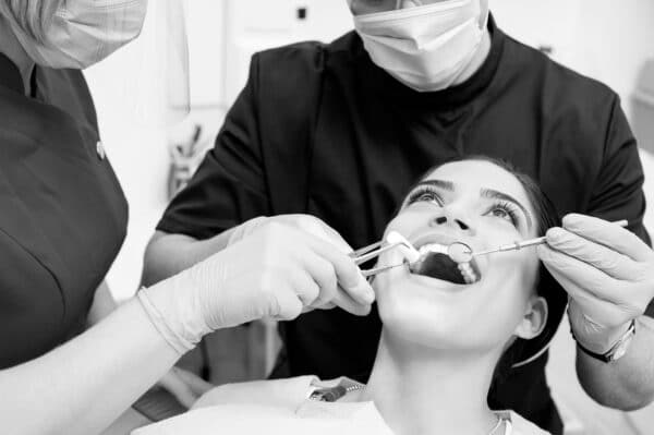 skipped dental checkups Dentist treating patient teeth with assistant