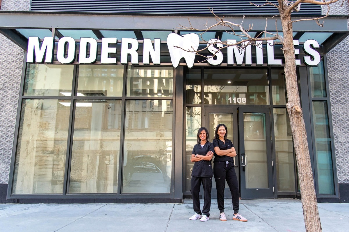 Modern-smiles-doctors-in-front-of-old-town-location Two female dentists standing confidently outside modern smiles dental office in old town, wearing black scrubs.