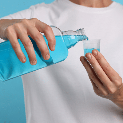 Closeup of a man pouring mouthwash into a small plastic cup, representing the benefits of mouthwash