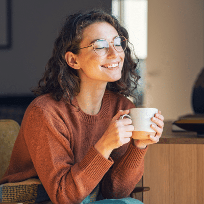 Best way to remove teeth stains 4 Woman holding a cup of coffee, cozy setting, representing the best way to remove teeth stains